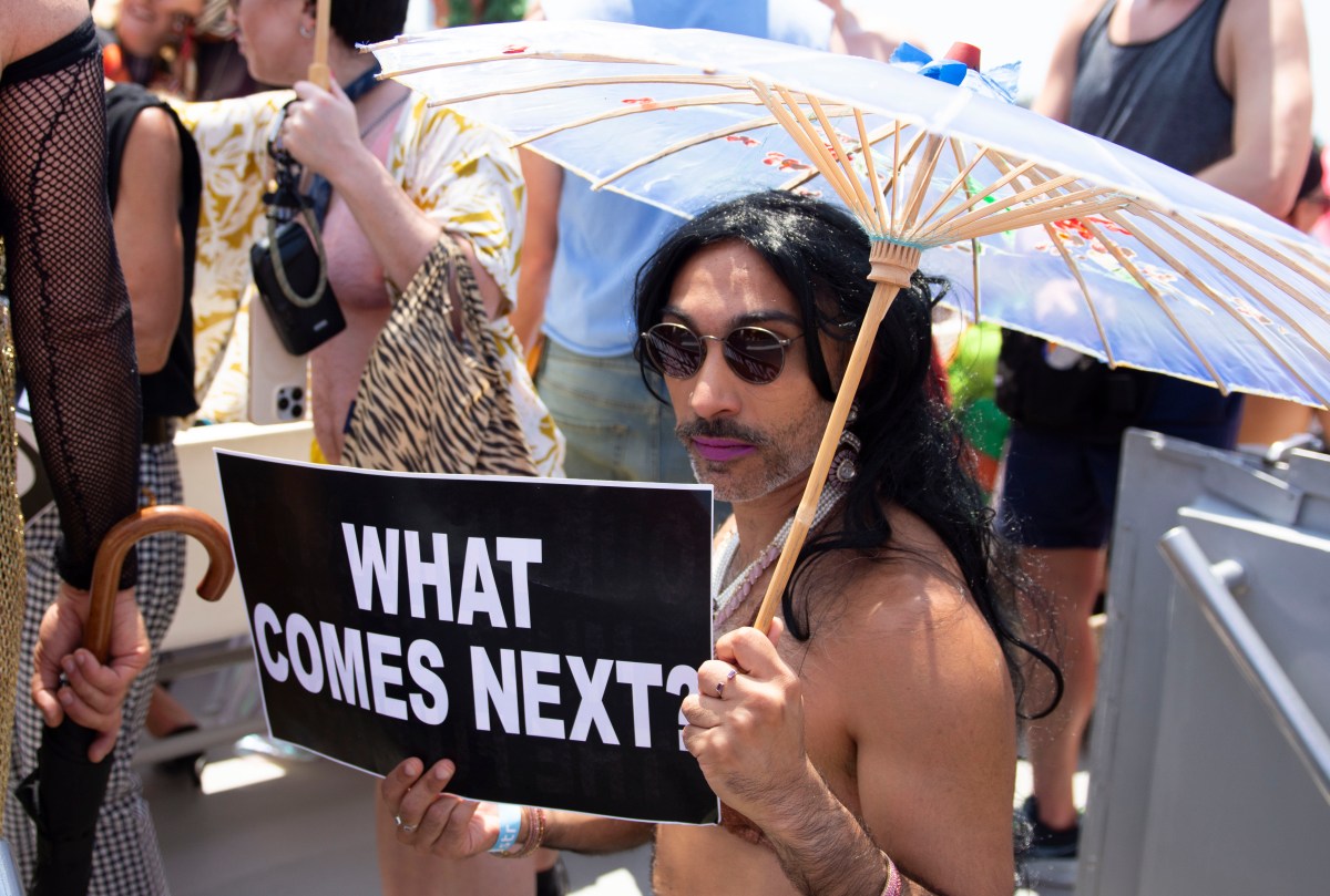 an attendee of the 50th invasion of the pines holds a sign that says WHAT COMES NEXT?