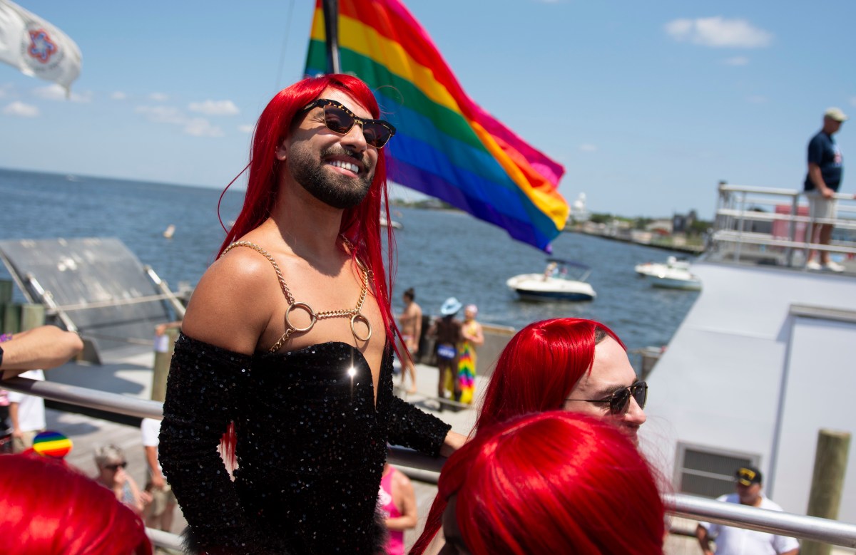 an attendee of the 50th invasion of the pines wears a long red wig while smiling on the ferry