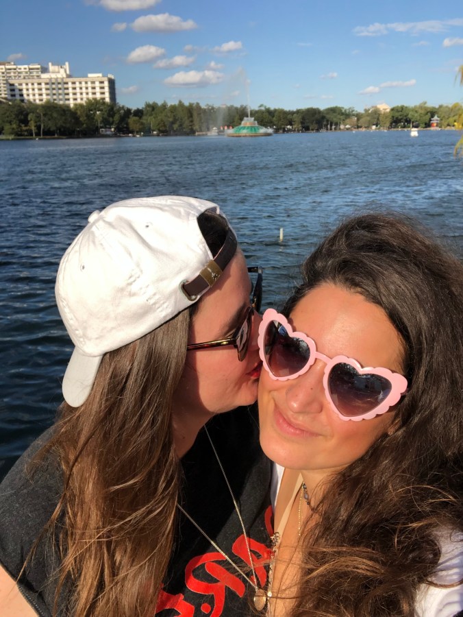 Kristen kissing Kayla's face in front of a lake