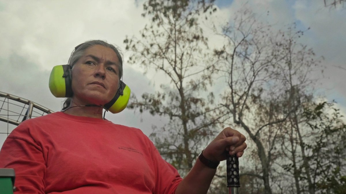 Betty Osceola in an orange shirt and ear covers in River of Grass