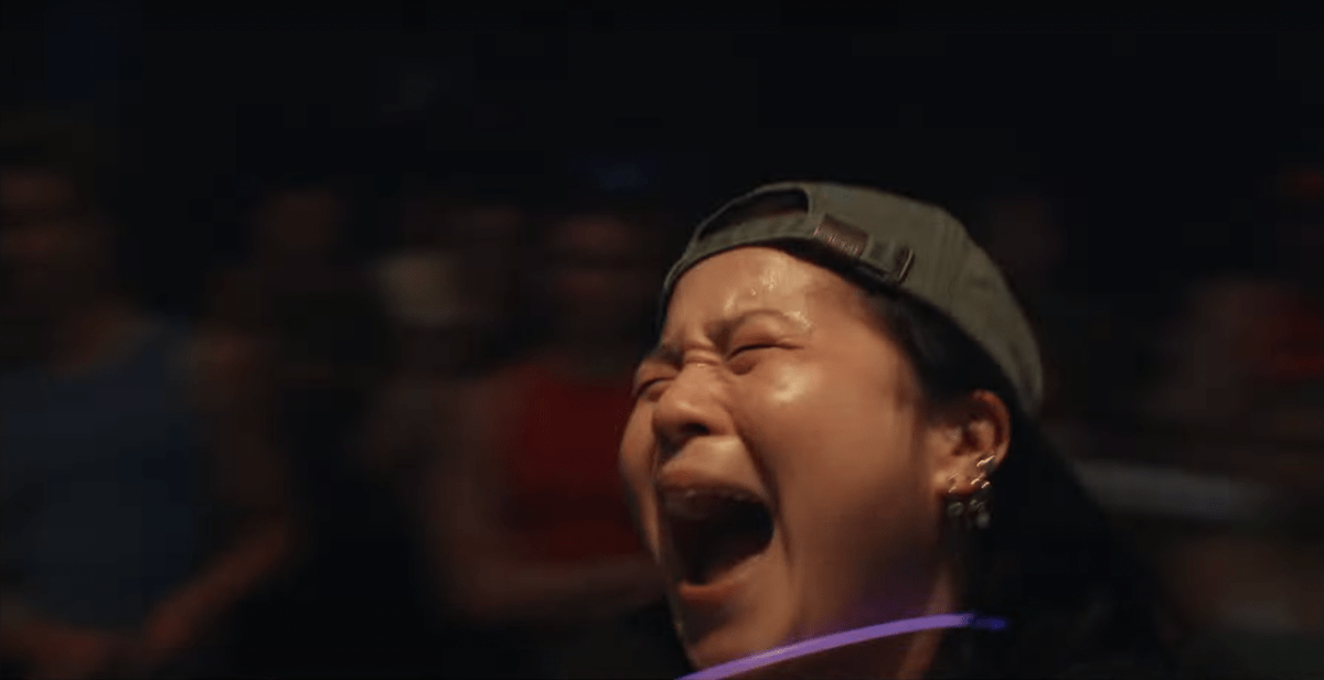 best lesbian night club scenes: Kelly Marie Tran spins around with a glow stick necklace and backward hat