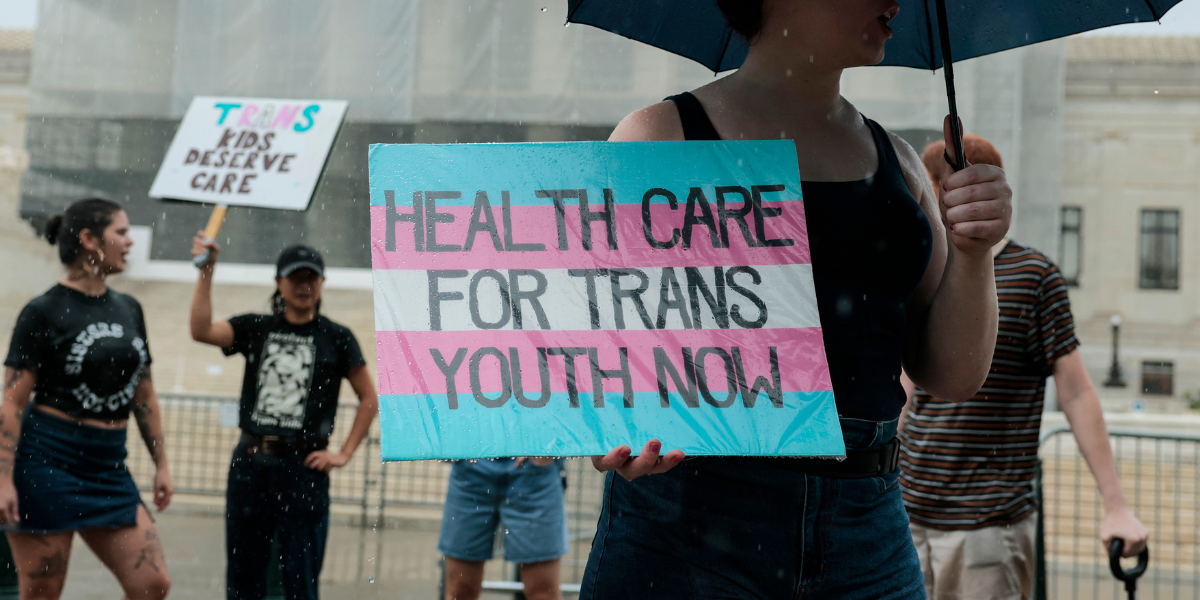 a sign that says HEALTH CARE FOR TRANS YOUTH NOW