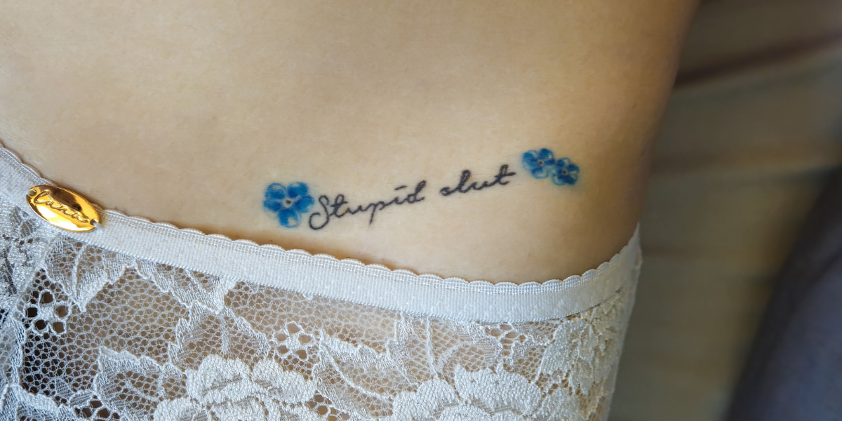 a body with the words stupid slut tattooed on