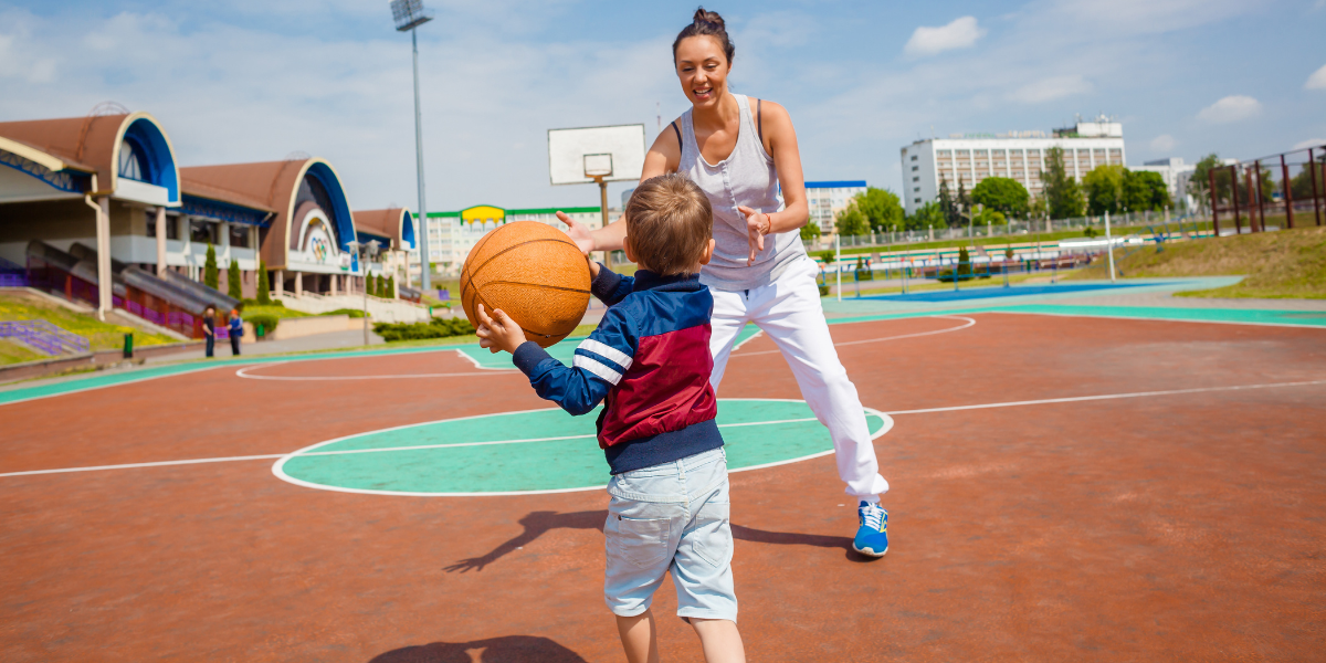 a mom playing basketball with her son